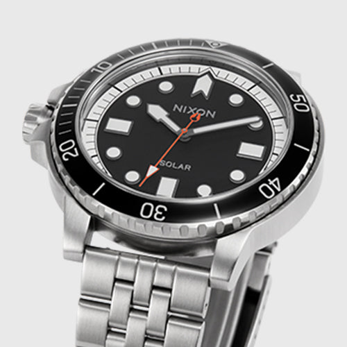 Nixon Solar analog watch with black face, stainless steel band, and black bezel.