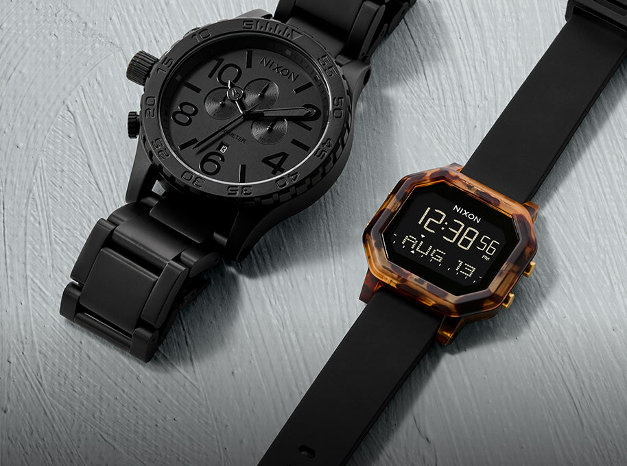 Two Nixon watches: a black analog watch with a metal band and a digital watch with a tortoise shell case and black rubber strap.