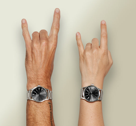 Hands wearing large Nixon watches